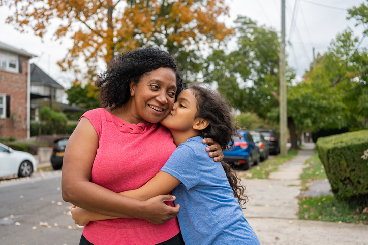 An older child kisses her mother on the cheek